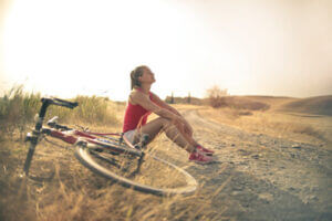 woman sitting outdoors next to a bike